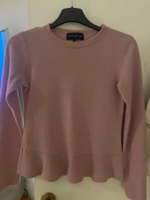 Ljusrosa stickad tröja från STOCKH LM - Supersöt ljusrosa stickad tröja från STOCKH LM med rund halsringning och volangkant nedtill. Tröjan har långa ärmar och är gjord av ull. Storleken är xs men jag uppskattar den mindre, tror att den har krympt i tvätten. Finns ett litet hål som jag kan laga. 