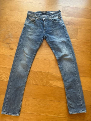 Blå slim fit jeans från Replay - Snygga blå straight fit jeans från Replay med klassisk femficksdesign och dragkedja. Jeansen har en lätt tvättad look och raka ben. Perfekta för dig som gillar en avslappnad men stilren vibe. Storleken är: W28 L32