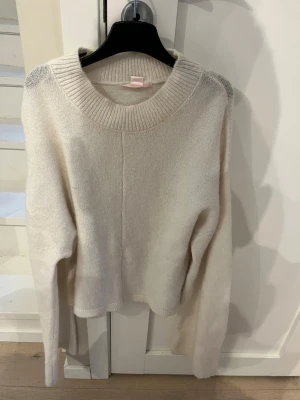 Vit stickad tröja från Gina Tricot - Mysig vit stickad tröja från Gina Tricot med rund halsringning och ribbade muddar. Tröjan har en avslappnad passform och är perfekt för lager-på-lager. Enkel och stilren design som passar till det mesta.