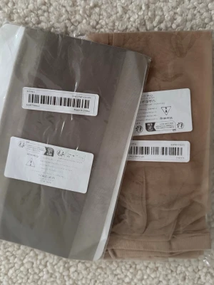 2-pack tights grå & beige one size - Säljer ett 2-pack tights i färgerna grå och beige. Tightsen är tunna och stretchiga, perfekta att bära under kjol eller klänning. One size och tillverkade i Kina. Materialet känns mjukt och följsamt.