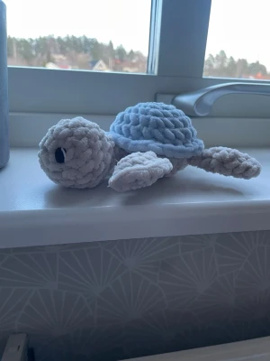 Virkad sköldpadda  - Supersöt handvirkad sköldpadda med beige hud och ljusblått skal. Svarta broderade ögon vilket gör att den är säker även för små barn. Perfekt som dekoration eller gosedjur, och även att ge bort i present. Tillverkad i fluffigt, tjockt garn som känns riktigt mysigt. Om man köper både denna och en rosa jag har i min profil kanske man kan ha det som gender reveal dekorering eller liknande? (Bara en idé) 