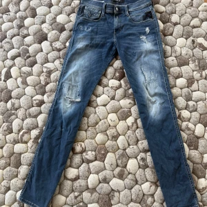 Blå slim fit jeans från Anbass - Snygga blå slim fit jeans från Anbass med slitningar och distressed detaljer på benen. Jeansen har klassisk femficksmodell och är tillverkade i Hyperflex-material för extra stretch och komfort. Perfekta för en avslappnad och trendig look.