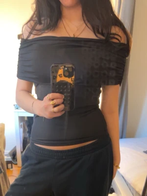 Svart offshoulder topp från H&M Divided - Säljer en svart offshoulder topp från H&M Divided. Toppen är axelbandslös och har en tight passform som framhäver figuren. Perfekt till ett par höga jeans eller kjol. Materialet känns mjukt och stretchigt.