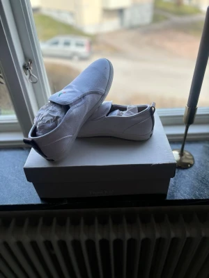 Vita sneakers från Patrick. Finns i massor olika storlekar på alla olika modeller. - Stilrena vita sneakers från Patrick i canvasmaterial med klassisk låg profil. Skorna har en broderad logga i grönt, rött och svart på sidan och vita snören. Perfekta för dig som gillar enkel och clean stil.