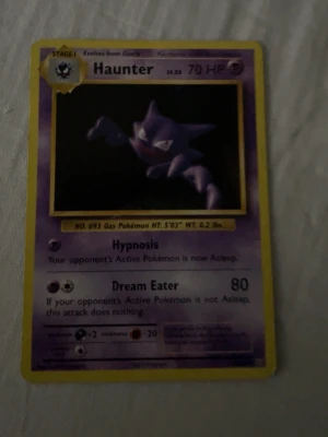 Pokémonkort Haunter 70 HP - Samlarobjekt! Ett klassiskt Pokémonkort med Haunter, 70 HP, från den ursprungliga serien. Kortet har lila och gul ram, med Haunter i mörka färger på framsidan och den ikoniska Pokéball-designen på baksidan. Perfekt för dig som gillar Pokémon eller samlar på kort.