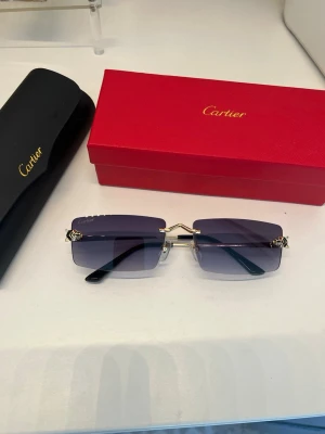 CARTlER SOLGLASÖGON  - Exklusiva Solglasögon! Säljer ett par otroligt eleganta solglasögon ur den ikoniska Panthère-kollektionen. En tidlös modell som kombinerar lyx med en modern, minimalistisk estetik. Detaljer: Modell: Panthère Farg: Guldfärgade detaljer med vackert tonade glas i en blå/lila gradient. Skick: Fin skick Tillbehör: Säljes komplett med originalfodral (svårt läderfodral) och den klassiska röda boxen. Övrigt: Nypris för dessa ligger runt 11 000 - 12 000 kr.