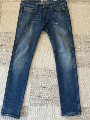 Blåa replay anbass jeans  - Replay Anbass jeans i blå tvätt, storlek 33/34, slim fit. Snygg passform med fades och diskreta slitningar som ger en trendig look. Passar bra till både vardag och mer uppklätt. Hör gärna av dig om du har några frågor!
