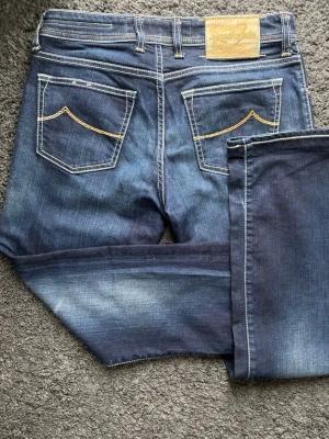Jacob Cohën 620 Comfort  - Exklusiva Jacob Cohën. Perfekt denim med en magisk tvätt! 🧵 Märke & Modell: Jacob Cohën - J620 Comfort 📏 Storlek & Passform: Storlek 31. Rak modell. 🧩 Material: 93% bomull, 6% polyester, 1% spandex 📐 Mått: Midja: 39 cm Innerben: 76 cm Ytterben: 99 cm ✅ Skick: 8,5/10 - Mycket fint skick! Lite slitna längst ner på ena benet och några hårstrån borta från patchen. ✨ Detaljer: Silverpläterade knappar, snyggt broderad text, läderpatch. 💰 Nypris: Ca 4500 kr ‼️ Skickas inom 24h ‼️ 