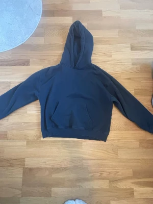Mörkblå hoodie från 157 - En enkel och stilren mörkblå hoodie från 157 med klassisk känguruficka framtill och huva. Hoodien har långa ärmar och ribbade muddar vid ärmslut och nederkant. Perfekt för en avslappnad look och passar till det mesta.