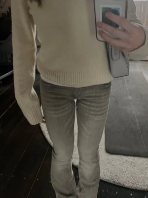 Gråa raka jeans med vintagekänsla - Säljer ett par gråa jeans med rak passform och lätt utsvängda ben. Jeansen har en snygg tvättad look och klassisk femficksdesign. Perfekta för en avslappnad och trendig stil.