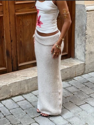 Beige stickad långkjol - Säljer en beige stickad långkjol från designbysi med bred, vikt midja. Kjolen har en rak och avslappnad passform och är perfekt för dig som gillar en mysig och trendig stil. Passar till både sneakers och sandaler. Helt oanvänd med prislapp kvar. Nypris: 453kr