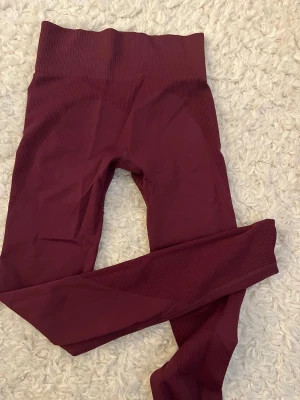 Vinröda seamless leggings 157 X-Small - Säljer ett par vinröda seamless leggings från 157 i storlek X-Small. De har hög midja och ribbade detaljer längs sidorna och midjan för extra komfort och snygg passform. Perfekta för träning eller chill dagar. Materialet är stretchigt och följsamt.