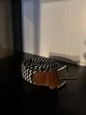 Svart vitt flätat bälte  - Ett riktigt snyggt flätat bälte. Bältet är svart vitt och passar till det mesta. Skicket är otroligt bra då de endast är använt någon enstaka gång. Skriv vid frågor och kolla gärna in min profil för fler bälten och kläder!