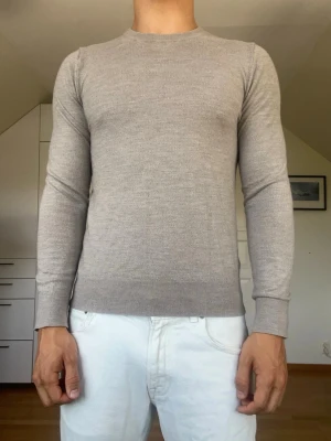 Beige stickad  tröja - Beige stickad tröja från Riley. Tillverkad i 100% merino ull. Strl S. Inga defekter. Modellen är 178 cm och väger 77 kg. Hör gärna av dig vid frågor!