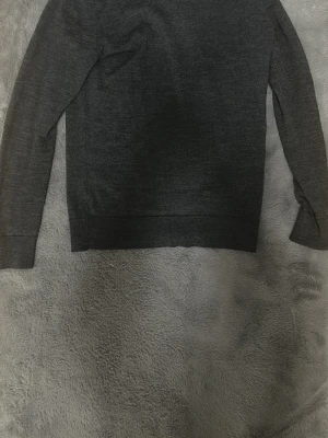 Mörkgrå merinoullströja H&M XS - Mörkgrå stickad tröja från H&M i mjuk merinoull. Klassisk rund halsringning och långa ärmar. Perfekt basplagg för lager på lager och enkel att matcha med olika stilar.