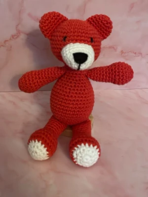 Virkad röd nalle - Säljer en handvirkad björn i rött och vitt garn. Björnen har rund mage, stora öron och vita detaljer på nos och tassar. Perfekt som dekoration eller present till någon som gillar söta mjukdjur. Sittande 11cm