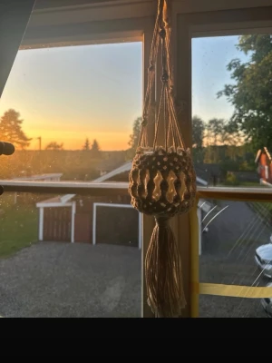 Makramé amplar med glasburk - Säljer två handgjorda makramé amplar i beige bomullssnöre med glasburk. Perfekt att hänga i fönstret för små växter eller dekoration. Snygg boho-stil med knutar och tofs nedtill. Glasburken är rund och genomskinlig.