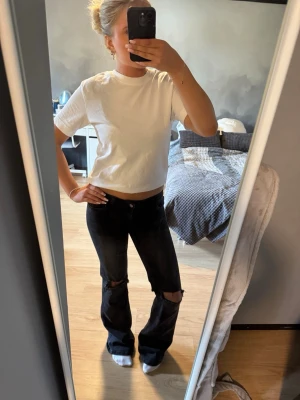 Svarta slitna bootcut jeans från Nelly - Säljer ett par svarta bootcut jeans med slitningar över knäna. Jeansen har låg midja. Materialet är denim med en något stretchig känsla. De är från Nelly i storlek 34🥰