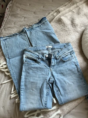 Ljusblå jeans från Gina Tricot - Säljer ett par ljusblå jeans från Gina Tricot i storlek 36. Jeansen har klassisk femficksdesign och knappar bak på fickorna! Billigt pris då jag sprättat upp dem nertill💛Skriv vid frågor! 