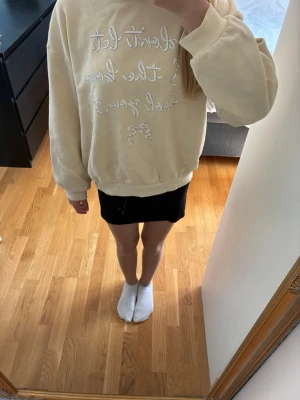 Gul sweatshirt från Lindex - Mysig beige sweatshirt från Lindex med tryckt text och rosett framtill. Tröjan har rund halsringning, ribbade muddar vid ärmslut och nederkant samt mjuk insida i fleece. Perfekt för en avslappnad och trendig look. Den är aldrig använd bara testad.