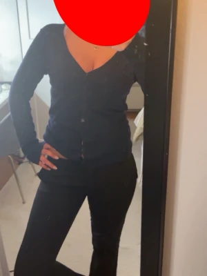 Svart v-ringad kofta med knappar - Snygg svart kofta med v-ringning och knäppning framtill. Skriv för fler bilder! Långärmad modell som sitter figurnära och passar perfekt till olika outfits. Enkel och stilren design utan synligt märke.