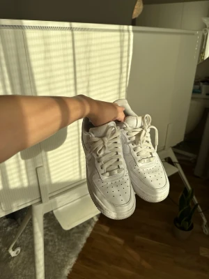 Vita klassiska Nike sneakers. - Säljer ett par vita sneakers med låg profil och snörning. Skorna har perforerade detaljer på tån för ventilation och en tjock sula för skön komfort. Tillverkade i syntetmaterial och passar perfekt till streetwear eller casual outfits.