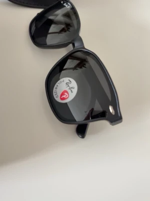 Svarta Ray-Ban Wayfarer solglasögon - Säljer ett par klassiska svarta Ray-Ban Wayfarer solglasögon med polariserade linser. Snygg och tidlös design med Ray-Ban-logga på glaset och skalmen. Kommer med originalfodral och box.