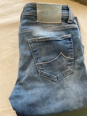 Ljusblå raka jeans med fickdetalj - Säljer ett par ljusblå jeans med raka ben och snygg fickdetalj bak. Jeansen har klassisk femficksmodell och en ljus tvätt som ger en avslappnad vibe. Perfekta till sneakers eller boots och passar till många olika stilar.