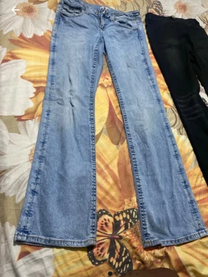 Ljusblå bootcut jeans - Säljer ett par ljusblå bootcut jeans med klassisk femficksdesign och normal midja. Jeansen har en lätt utsvängd passform nertill och är tillverkade i denim. Perfekta för dig som gillar en retroinspirerad stil.