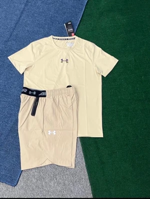 Beige träningsset från Under Armour - Snyggt träningsset från Under Armour i beige, består av en kortärmad t-shirt och matchande shorts med elastisk midja och logga på både tröja och shorts. Perfekt för gymmet eller löprundan. Materialet är lätt och andas bra.