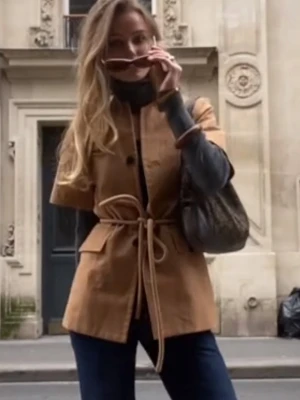 Kortärmad beige kavaj med knytskärp - Stilren beige kavaj med korta ärmar och knytskärp i midjan. Kavajen har två stora fickor framtill och stängs med knappar. 