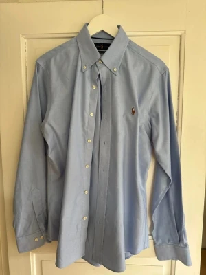 Blå ralph lauren skjorta - Blå ralph lauren skjorta i otroligt skick, inga defekter eller tecken på slit. Passar m, skriv om du har frågor