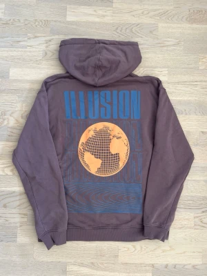 Vailent hoodie med tryck - lila, M - Mycket bra skick. Inga tydliga tecken på användning. Hoodie från Vailent, storlek M, lila Huva med snörning, stor framficka, litet tryck fram, stort tryck bak samt en liten logga vid ena ärmslutet Bröstvidd: 61 cm Längd: 73 cm 100% bomull Inga defekter