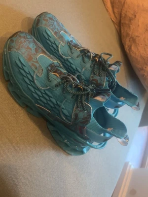 Turkosa chunky sneakers med mönster - Säljer ett par riktigt unika turkosa sneakers med chunky sula och coola detaljer i silver och grått. Ovandelen är i mesh och syntet med ett vågigt mönster på sidorna och reflekterande partier. Skorna har matchande snören och en futuristisk vibe.