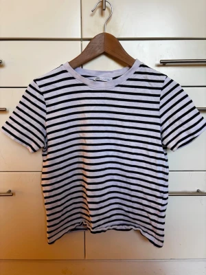 Randig vit och svart t-shirt i stadig bomull från Zara storlek S - Säljer en klassisk vit t-shirt med svarta horisontella ränder. T-shirten har rund halsringning och korta ärmar. Materialet är bomull. Från Zara storlek S