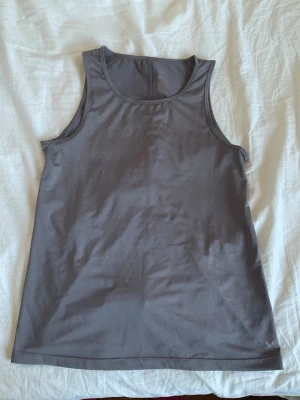 Grå linnetopp från SOC - Snygg grå linnetopp från SOC i mjukt och stretchigt material. Perfekt för träning eller en chill vardagslook. Ärmlös design med rund halsringning och enkel stil som är lätt att matcha med andra plagg.