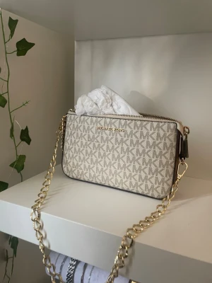 Beige Michael Kors handväska - Snygg beige handväska från Michael Kors med MK-logga över hela väskan. Kommit till användning ändast 5 gånger❤️