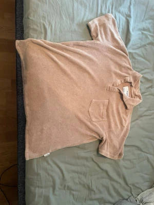 Beige frotté polotopp från Selected - Snygg beige polotopp från Selected med kort ärm och bröstficka. Tillverkad i mjuk frotté