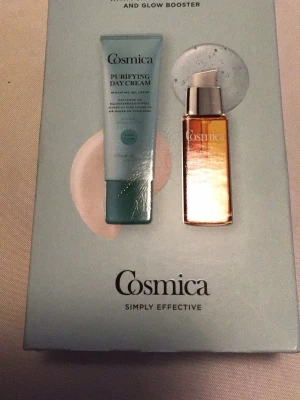 Cosmica Purifying Day Cream & Glow Booster - Set med Cosmica Purifying Day Cream (50 ml) och Glow Booster (30 ml). Dagkrämen kommer i en ljusblå tub och boostern i en genomskinlig pumpflaska med orange innehåll. Perfekt för dig som vill ha återfuktad och strålande hud.