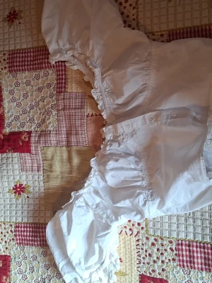 Vit croppad blus med puffärmar - Säljer en vit croppad blus med breda puffärmar och resår vid axlar och midja. Blusen har en romantisk vibe med volangdetaljer längs kanterna och är gjord i ett tunt, mjukt bomullstyg. Perfekt för dig som gillar trendiga och feminina plagg den är insydd kan spretas upp se bild Kan postas/ skickas 24/3.