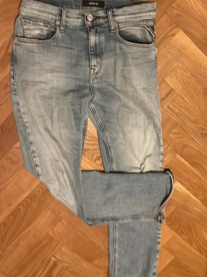 Ljusblå skinny jeans från replay - Säljer ett par ljusblå skinny jeans från replay med klassiska fem fickor och snygga slitningar. Jeansen har en smal passform, normalhög midja och detaljerade bakfickor med broderi. Perfekta för en avslappnad och trendig look. Obs fram fickorna har hål i sig men går att fixa enkelt