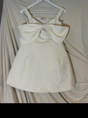 Vit studentklänning  - Vit studentklänning från NA-KD. Knappt använd. Tyvärr har en tråd gått sönder som håller i tyget runt (se bild ovan), men det påverkar inte när den sitter på. 