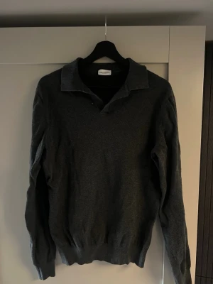 Mörkgrå stickad tröja John Henric - Snygg mörkgrå stickad tröja från John Henric med klassisk krage och v-ringning. Knappt använd, riktigt schysst.