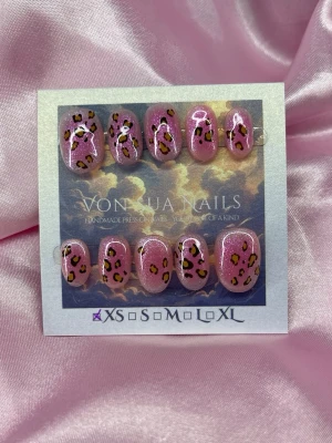 PinkLeo (XS);ExtraShortOval  - Snygga handgjorda press-on naglar i glittrigt rosa med handmålat leopardmönster i svart och gult. Naglarna har en oval form och är i storlek XS: 14 mm, 11 mm, 11,5 mm, 10 mm, 8 mm  . Perfekt för dig som vill ha en unik och trendig look.