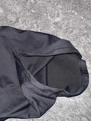 Svart halsvärmare från Select - Säljer en svart halsvärmare från Select. Den är tillverkad i mjuk och stretchig polyester, perfekt för att hålla värmen under kyliga dagar. Enkel design med diskret logga framtill. Snygg och funktionell accessoar för dig som gillar sportig stil.