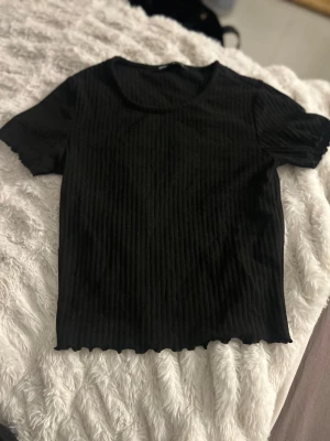 Svart ribbad topp från ONLY - Säljer en svart ribbad topp från ONLY i storlek XS. Toppen har korta ärmar, rund halsringning och är croppad i modellen. Aldrig använd 💞