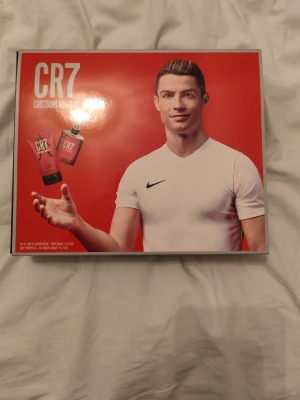 CR7 Cristiano Ronaldo parfymset - Snyggt parfymset från CR7 Cristiano Ronaldo med röd och svart design. Setet innehåller en parfym och en duschgel, båda med sportig och fräsch känsla. Kommer i en stilren svart och röd presentförpackning – perfekt för dig som gillar energiska dofter. Aldrig använd. Perfekt till ditt barn och även dig😀 här av er vid frågor och pris kan diskuteras vid snabb affär!