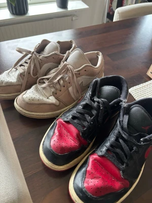 Nike Air Jordan 1 Low sneakers - Två par Nike Air Jordan 1 Low sneakers. Ena paret är beige med vita detaljer och det andra är svart med röda och vita detaljer. Säljer då jag ej vill skänka dom för vill att någon som faktiskt vill ha dom köper❤️ tar emot ungefär vilket pris som helst❤️ buda Järna , kan sälja båda tillsammans eller var för sig, båda är i storlek 41, dom är i dåligt skick men fungerar som skor, säljer båda för 150kr❤️