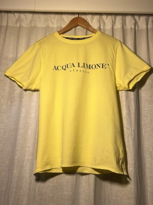 Gul t-shirt från Acqua Limone - Snygg gul t-shirt från Acqua Limone med klassisk logga tryckt på bröstet och en stor citronskiva med logga på ryggen. T-shirten har rund hals och korta ärmar. Perfekt för dig som ska ha kläder på dig i sommar! Storlek xs i utmärkt skick 10/10. Hör av dig vid minsta lilla fundering! Priset kan diskuteras vid snabb affär💪