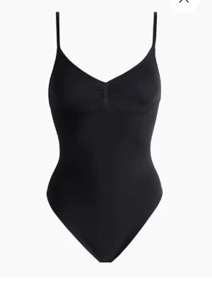 Skims dupe body - Stilren svart body med smala axelband och lätt rynkning vid bysten. Tillverkad i ett stretchigt och mjukt material som sitter skönt mot kroppen. Perfekt att bära under kläder eller som ett statement-plagg. Enkel och klassisk design.